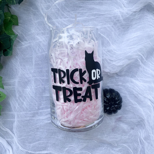 Trick or Treat clear glass can filled with pink crinkle paper on a white background.
