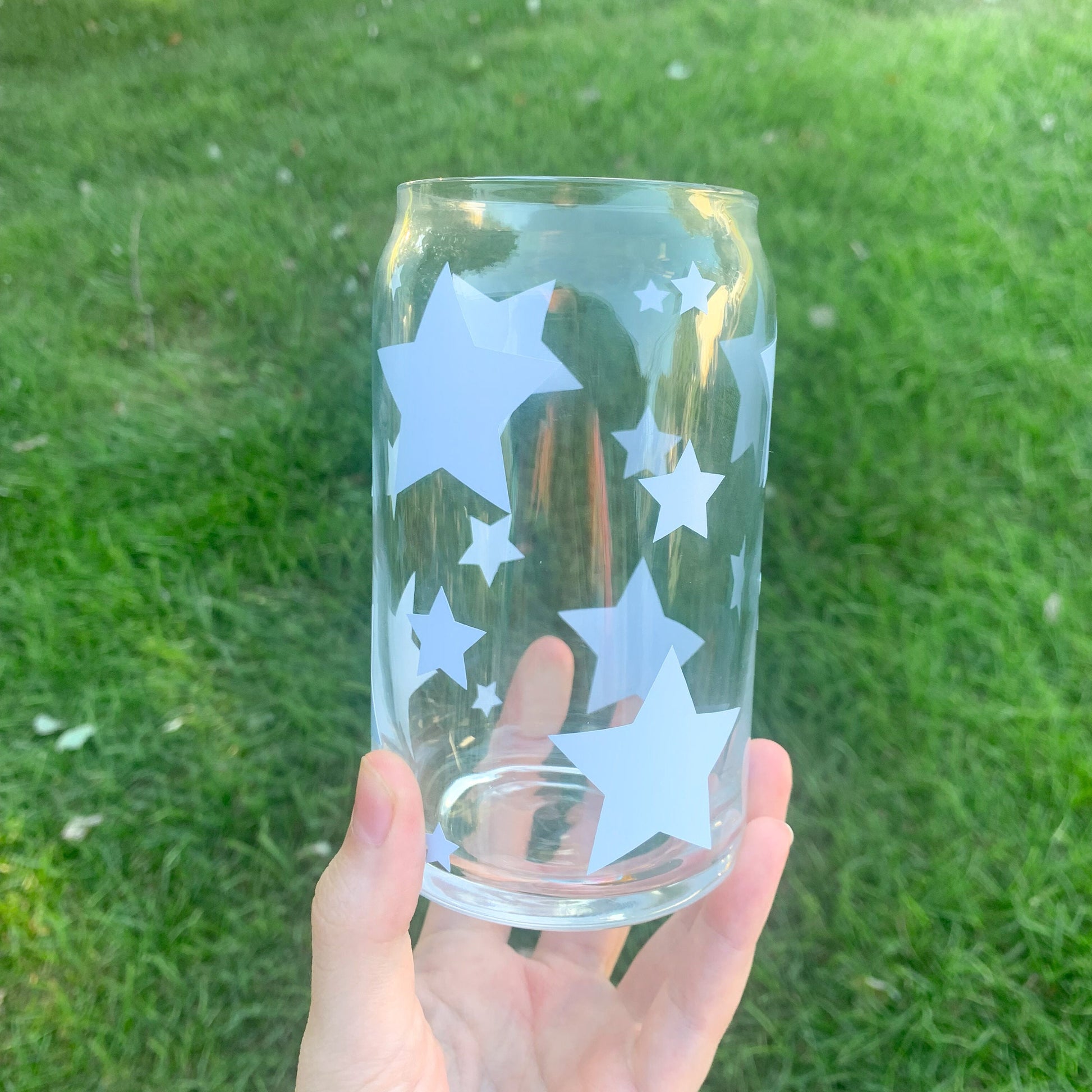 Empty blue star glass cup being held above green grass.