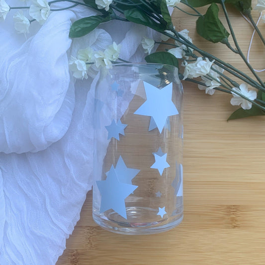 Light blue star clear glass can laying on a white and wooden background.