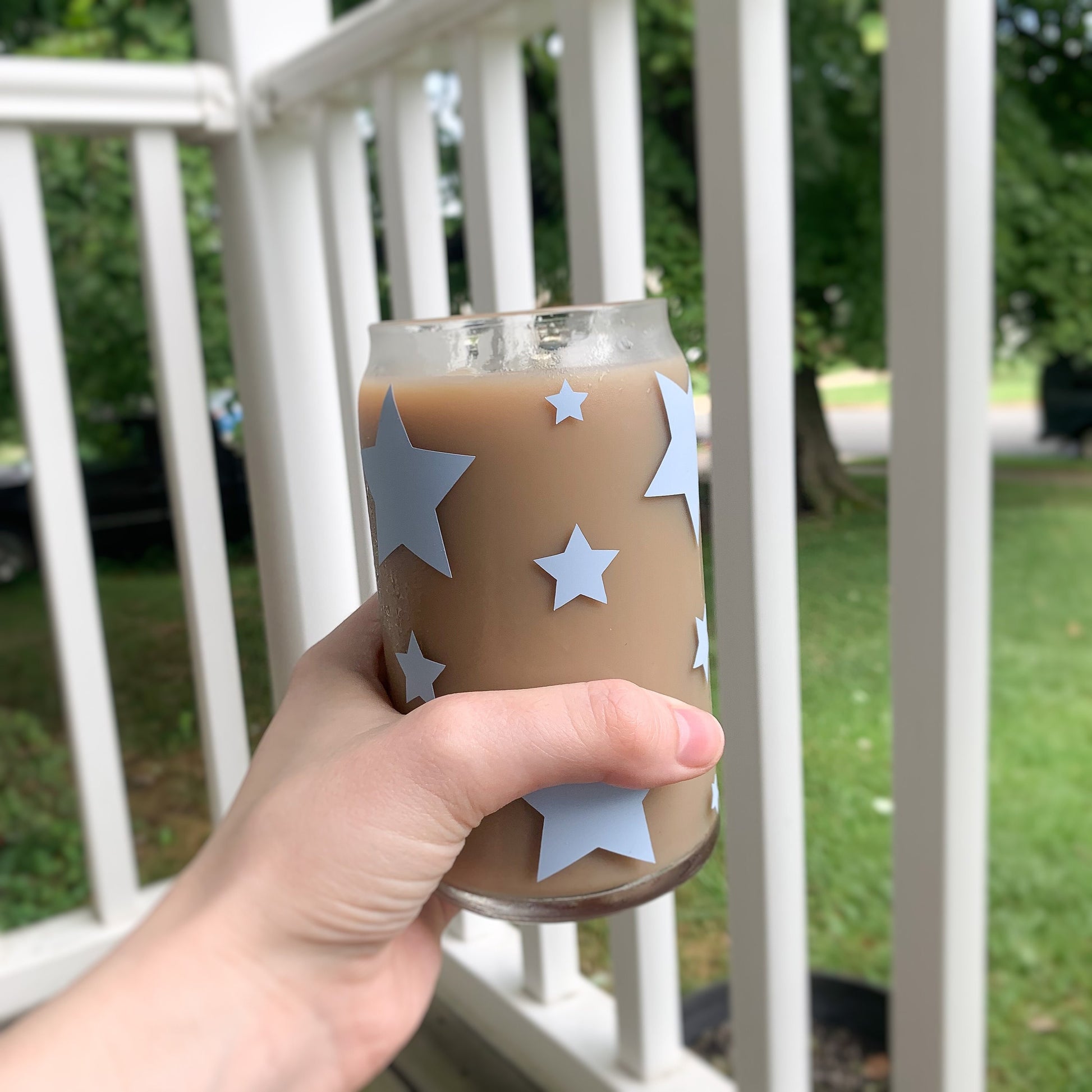 Cute glass cup with different sizes of light blue stars  being held by a hand. 